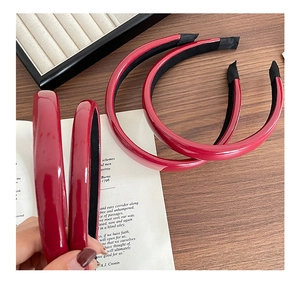 Detail view of red glossy PU leather headband with non-slip lining on wooden table