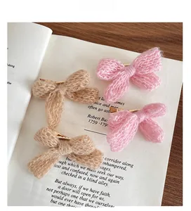 Detailed view of handmade knitted bow hair clips in pink and khaki on a book