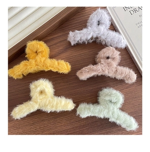 Détail de cinq pinces à cheveux en peluche colorées sur une surface en bois texturée
