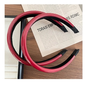 Detail view of two glossy red PU leather wide headbands with black non-slip fabric lining