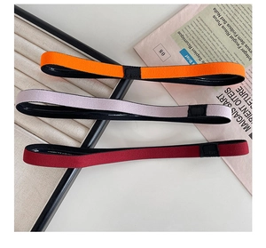 Close-up of three elastic sports headbands in orange, light purple, and burgundy textures