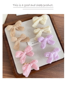 Detailed macro view of seven colorful knitted bow hair clips on a wooden display tray