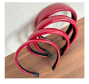 Detailed view of four dark red faux leather headbands showing shiny finish and black inner lining