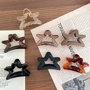 Matte and glossy star-shaped claw clips in six colors on a vintage magazine