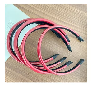 Close-up of four red faux leather headbands with glossy finish on a wooden surface