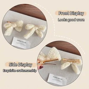 Pair of cream white knitted bow hair clips with textured yarn and gold metal clips