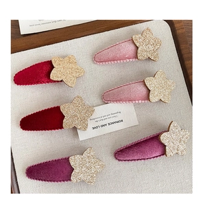 Detalle de clips de terciopelo con estrellas doradas brillantes para el pelo de niñas