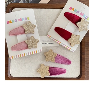 Detalle de horquillas de estrella de felpa en rosa y granate sobre tarjeta blanca