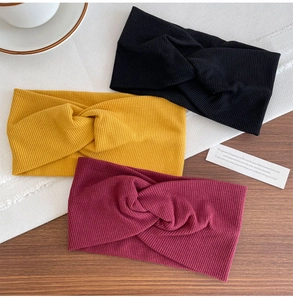 Detailed close-up of three ribbed knit cross headbands in black, mustard yellow, and burgundy