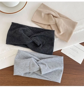 Close-up of three knitted ribbed knot headbands in beige, dark gray and light gray