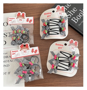 Close-up of black and white checkered bow hair clips with cute strawberry charms on wood