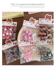 Close-up of six elastic hair ties with plaid bows and resin cartoon charms on a wooden desk