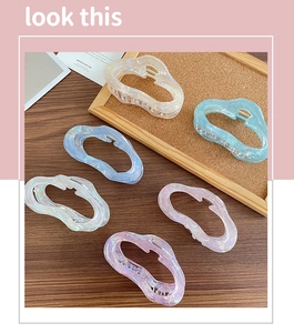 Iridescent jelly hair claws in macaron colors displayed on a wooden surface