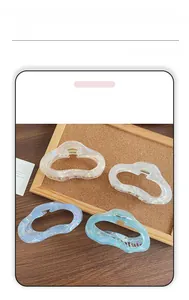 Detailed view of four iridescent resin hair claws in ivory, lilac, and blue shades