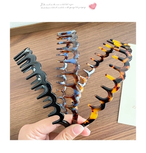 Detailed view of three wavy toothed headbands in black, marble blue, and amber shell