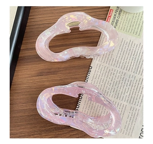 Detail view of large resin hair claws with pink-purple aurora texture and wavy design