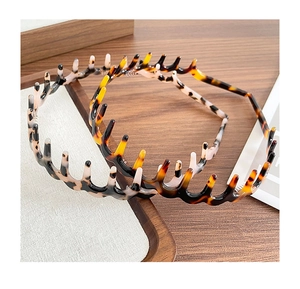Close-up of tortoise shell resin headbands with fine teeth on a wooden surface