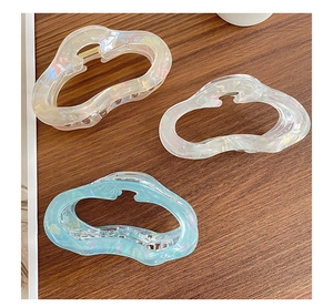 Detailed macro view of hollow wave hair claws in iridescent pink, white, and blue resin finish