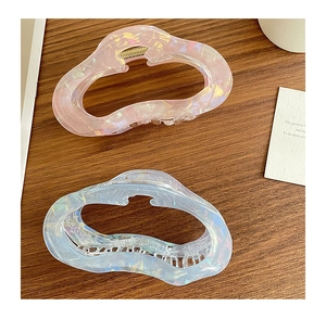 Close-up of hollow cloud hair claws with iridescent pearlescent finish on wood