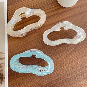 Elegant hollow wave hair claw clips with pearlescent finish in iridescent colors on wood