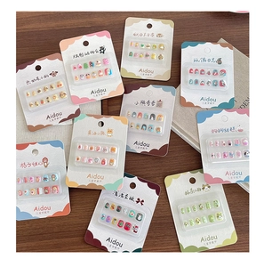 Detail view of 10 cartoon themed 3D press-on nail sets for kids on wooden surface
