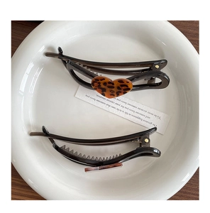 Detail view of two leopard print heart banana hair clips with internal comb teeth