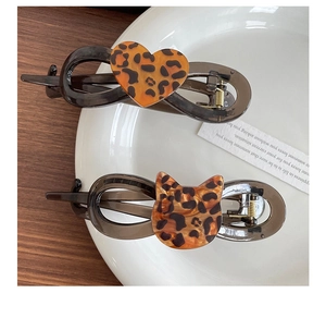 Close-up of leopard print heart and cat-shaped hair clips in a white ceramic dish