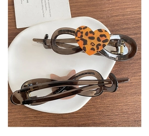 Detailed macro view of resin banana hair clips with leopard print heart on ceramic dish