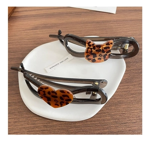 Detailed view of leopard print cat and heart shaped banana hair clips in a white plate