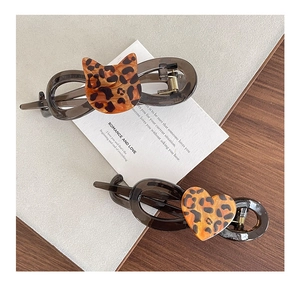 Close-up of leopard print acetate cat and heart hair clips with golden metal spring clips