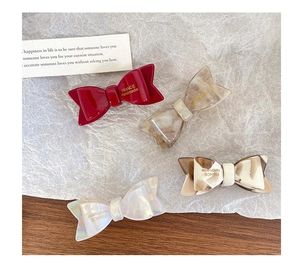 Détail de quatre pinces à cheveux noeud en acétate fait main en rouge, ambre et marbre