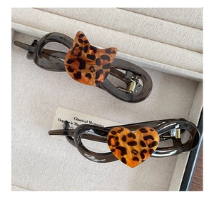 Detail of leopard print cat and heart resin hair clips in a beige jewelry box