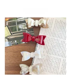 Détails de quatre barrettes à nœud en acétate aux couleurs rouge et motifs marbrés