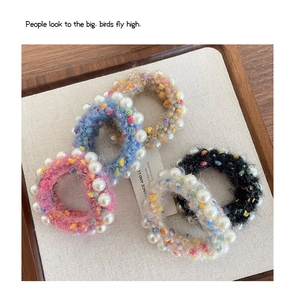 Détail de quatre chouchous en peluche colorés avec perles blanches et texture tricot