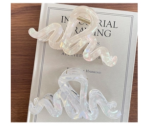 Détail de pinces à cheveux en acrylique ondulées avec fini rose nacré et iridescent