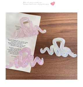 Vue macro de pinces à cheveux vagues françaises avec finition nacrée irisée rose et blanc