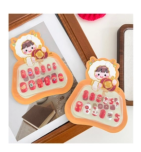 Close-up of festive press-on nails with cartoon dragon packaging and lion dance patterns