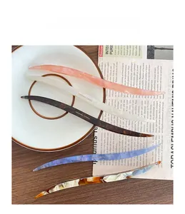 Detailed view of five colorful acetate hair sticks with marble textures on a white plate
