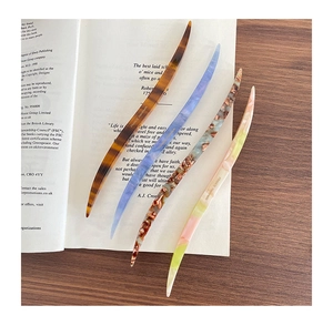 Detailed set of four curved acetate hair pins in marble and floral patterns on book