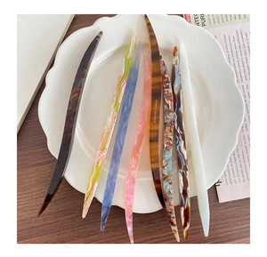 Close-up of tortoise shell and marble acetate hair sticks on a white plate