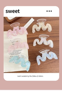 Dettaglio di fermagli per capelli ondulati cangianti in colori pastello perlati