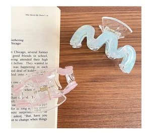 Dettaglio di fermagli per capelli ondulati iridescenti azzurro e rosa su legno