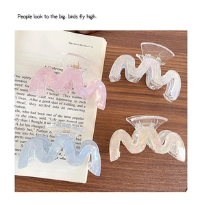 Quattro fermagli per capelli ondulati iridescenti in colori pastello su un libro