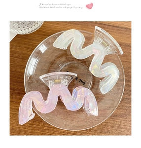Dettaglio di fermagli per capelli ondulati in acrilico iridato rosa e bianco