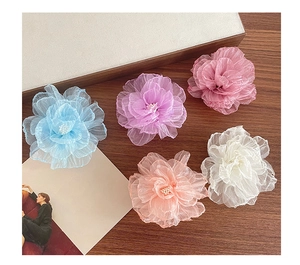 Detail von fünf Organza-Blumen-Haarspangen in Blau, Lila, Pink und Weiß mit Perlenmitte
