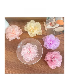Detaillierte Nahaufnahme von fünf farbigen Organza-Blumen-Haarspangen in einer Glasschale