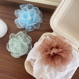 Drei elegante Haarspangen aus Organzablumen in Blau, Minze und Braun auf Holzoberfläche