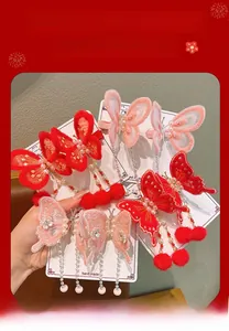 Détail de pinces à cheveux papillon rouges et roses avec pompons et perles pour filles