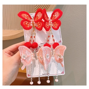Détail de pince à cheveux papillon faite main avec broderie, pompons et longues franges