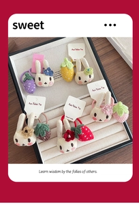 Détail de chouchous élastiques avec lapins en peluche tricotés et breloques de fruits